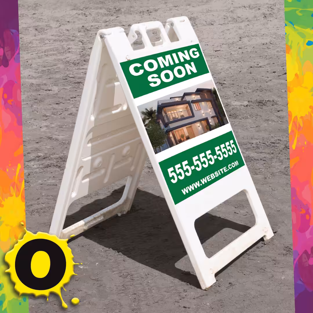 White A-frame sidewalk sign on gray pavement, displaying COMING SOON above a modern house photo, with a phone number and website link below. Bright, colorful border surrounds the image.