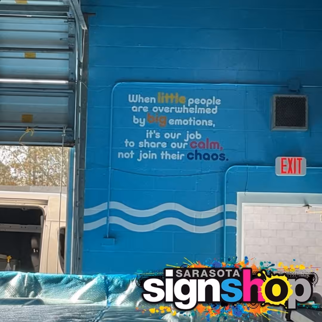 A quote on a blue wall reads: When little people are overwhelmed by big emotions, it’s our job to share our calm, not join their chaos. The Sarasota Sign Shop logo is at the bottom—vinyl applications made easy with removable and repositionable vinyl.