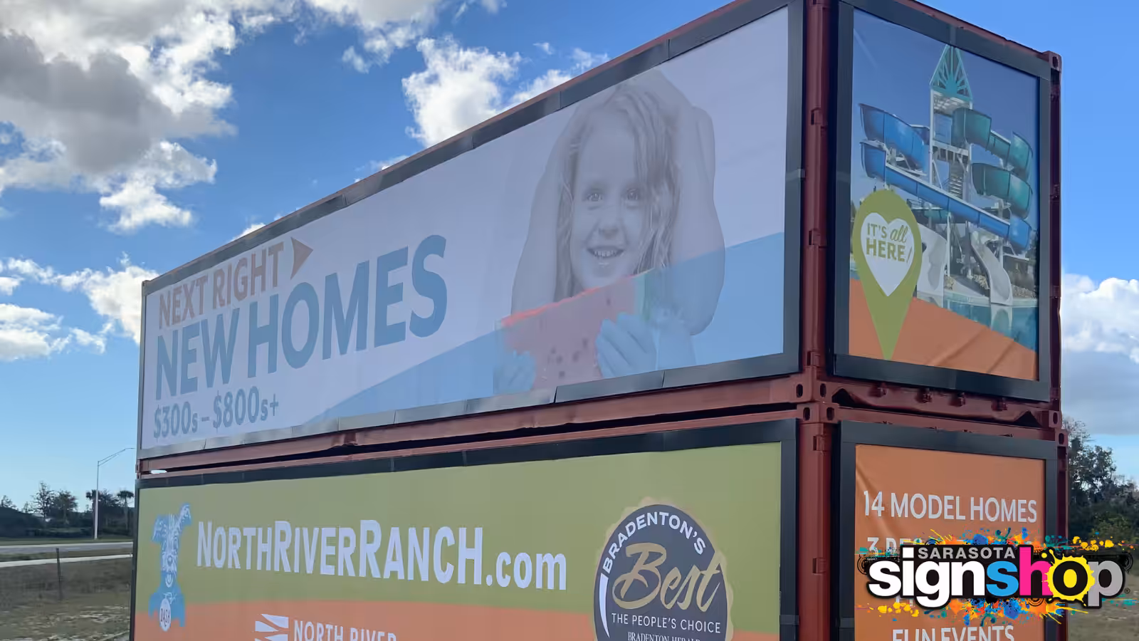 Billboard advertising new homes for $300K-$800K at North River Ranch, featuring a smiling child, a water park image, and UV resistant signage with local business logos against a blue sky and clouds.