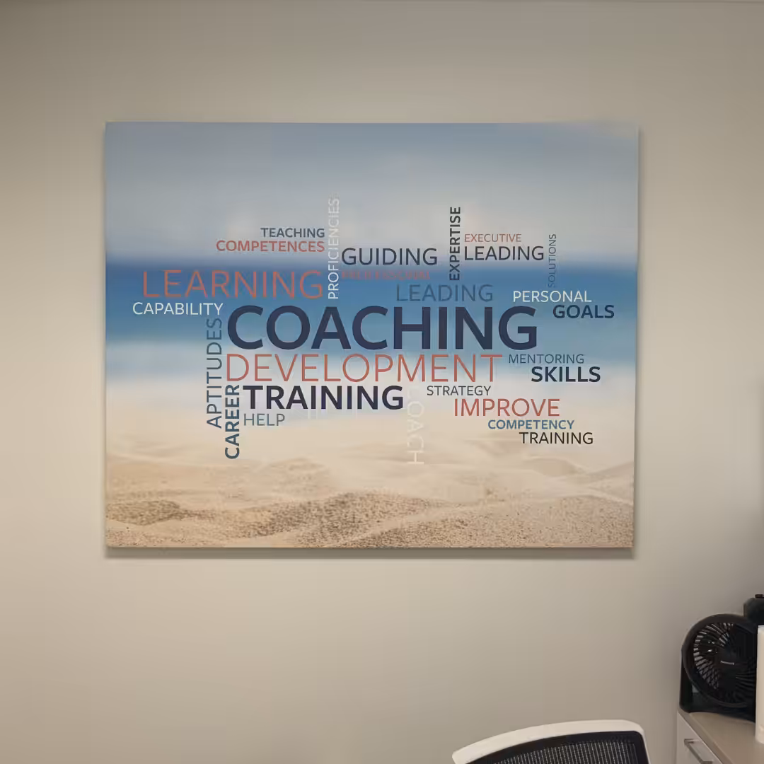 Word cloud art featuring words like COACHING, LEARNING, and SKILLS on a beach background, displayed above an office chair and equipment—an inspiring touch among your indoor business signs.